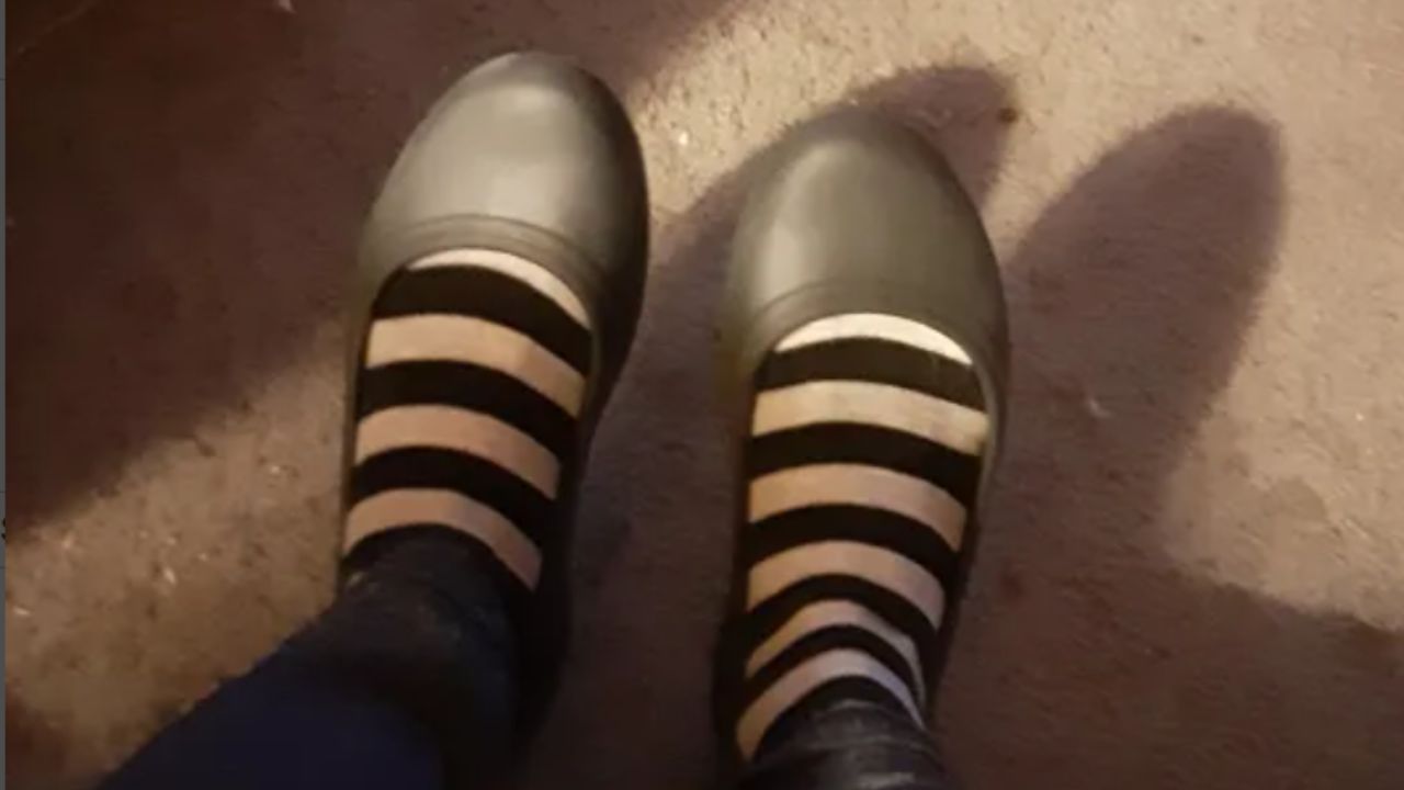 Woman wearing a pair of Crocs flats, with a pair of striped socks!