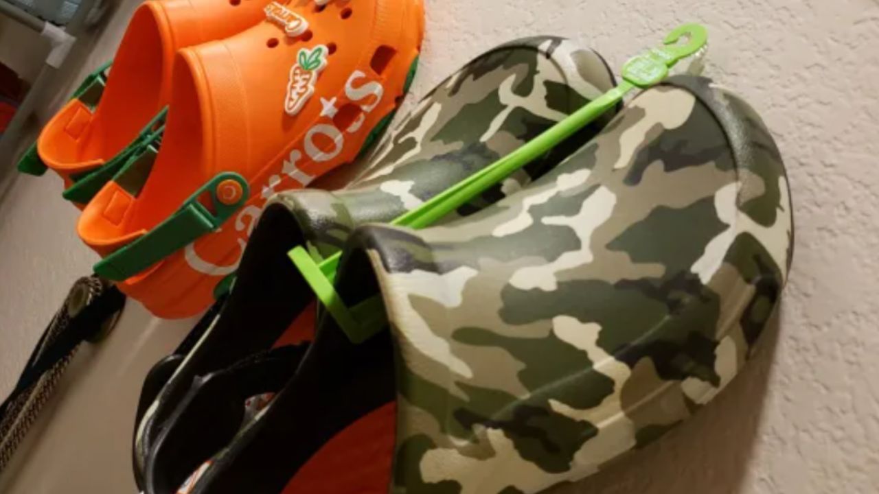 Pair of orange kids Crocs with Jibbitz of carrots on the toe, and a pair of men's camo Crocs.